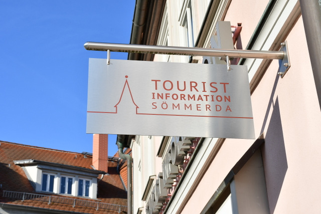 Ein Metall-Ausleger mit der stilisierten Silhouette von Sömmerda sowie dem roten Schriftzug Tourist Information Sömmerda prangt außen an der Einrichtung.